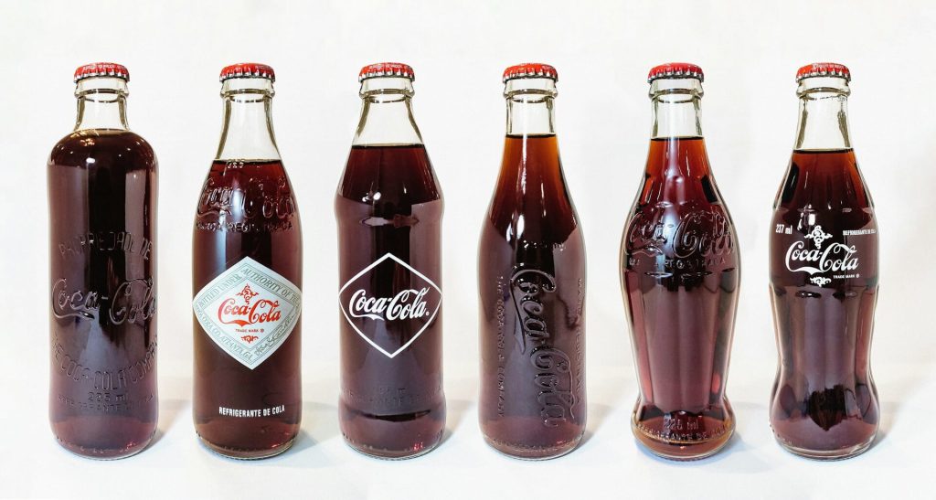 Row of commemorative Coca-Cola bottles from different years