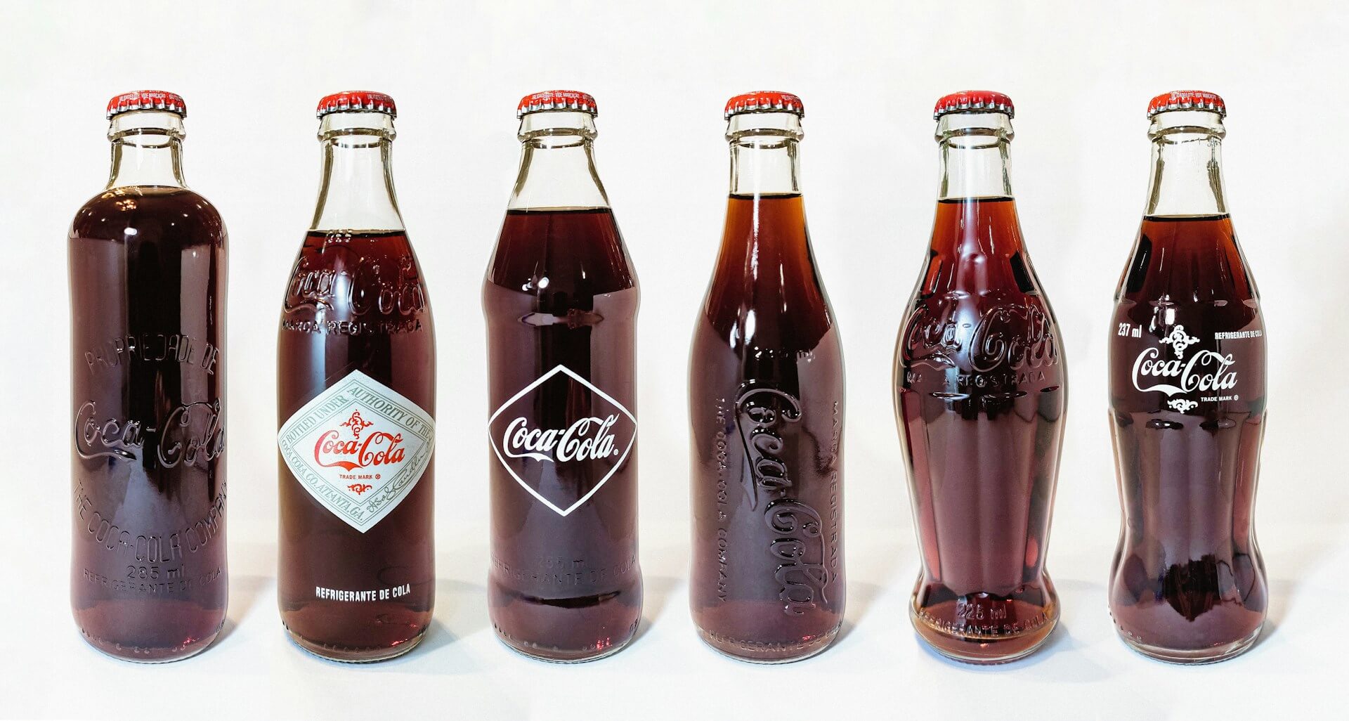 Row of commemorative Coca-Cola bottles from different years